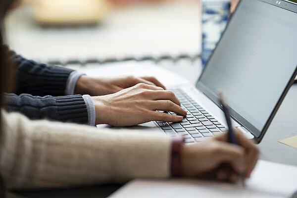 Two people working in front of a laptop